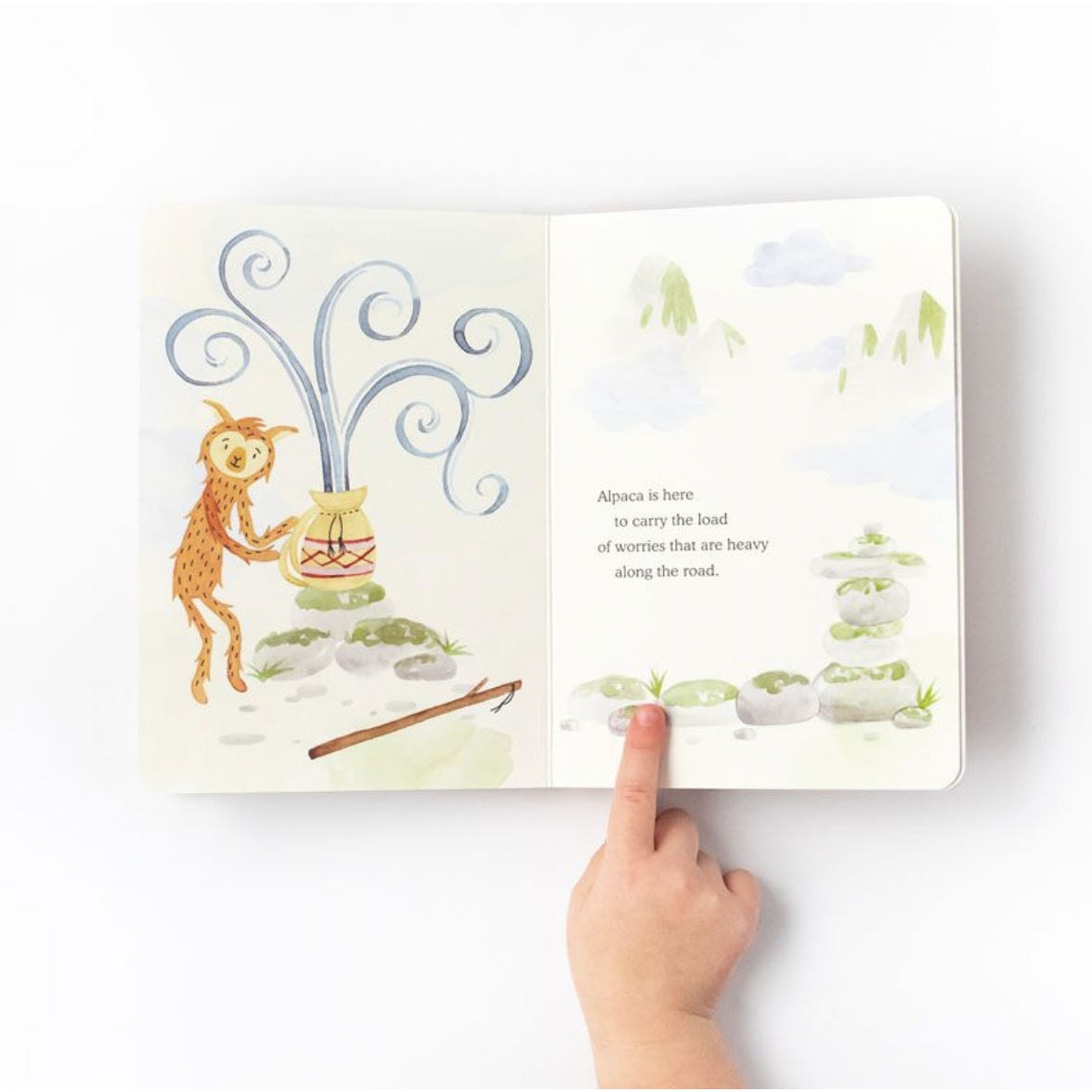 child&#39;s finger keeping the page open on the slumberkins alpaca board book